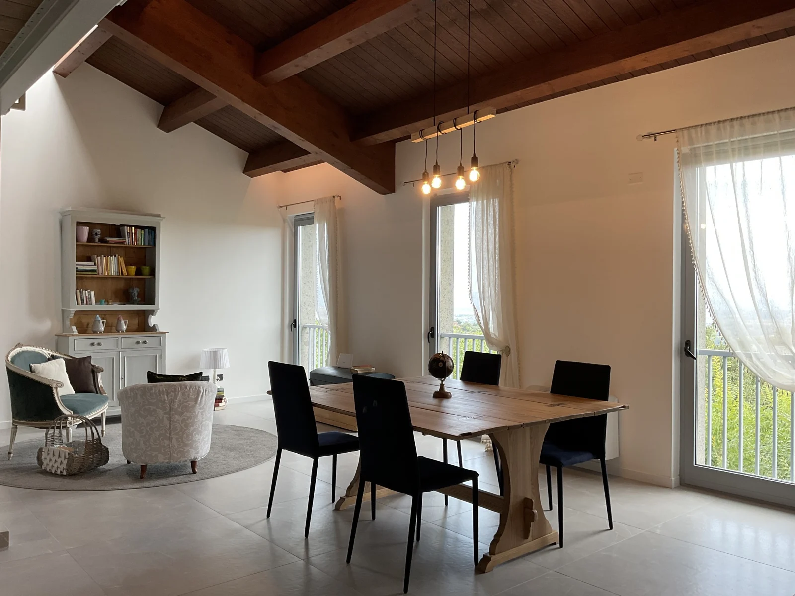 Spazio giorno condiviso con sedute, tavolo e finestre luminose
